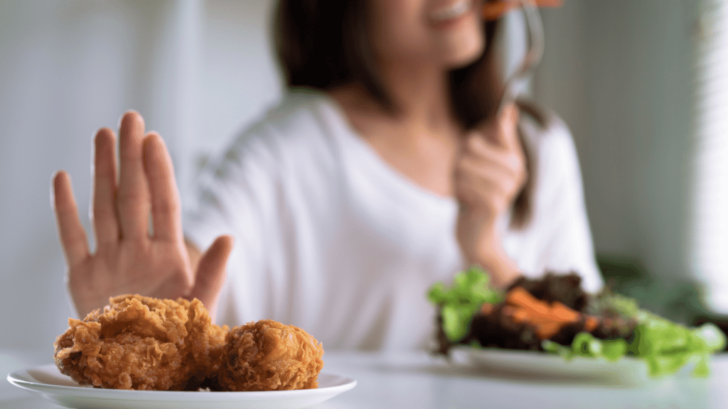 Mulher comendo comida saudável enquanto rejeita um prato de frango