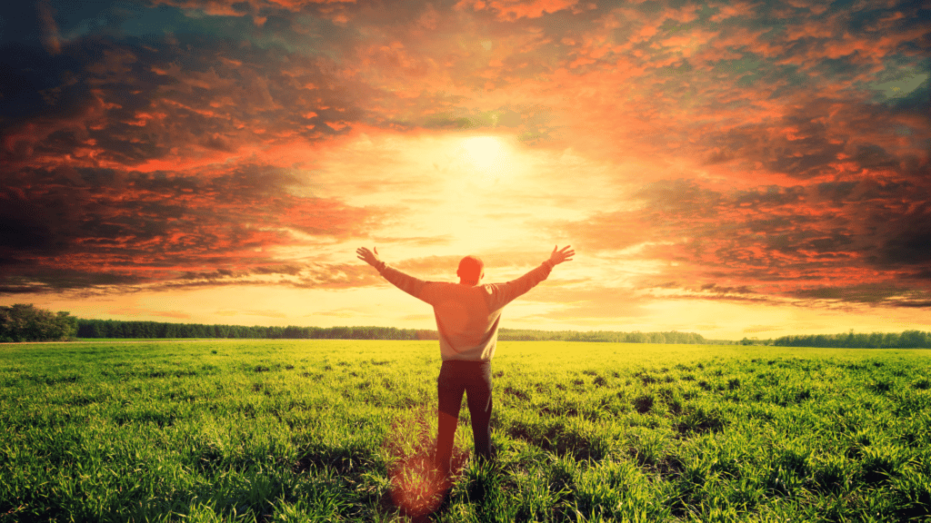 Homem de costas em meio a natureza com os braços abertos