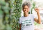 Uma mulher sorridente portando uma camiseta cuja inscrição é a frase "go vegan".