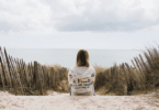 Mulher sentada de frente para o mar em uma praia