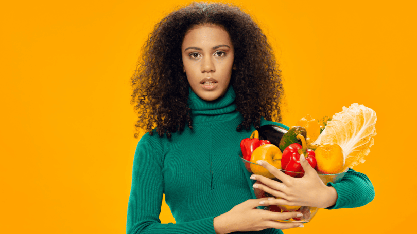 Mulher negra segurando uma vasilha cheia de alimentos saudáveis