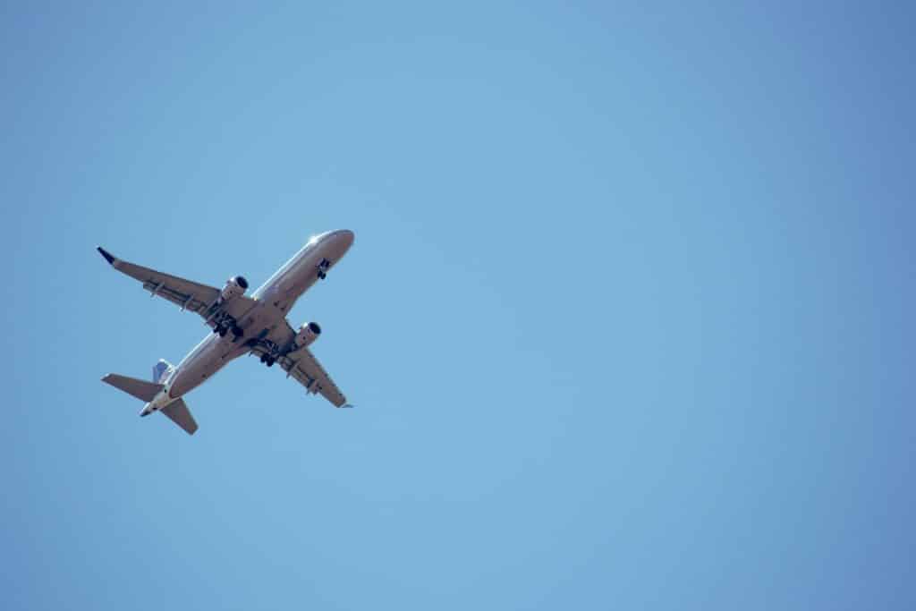Avião visto de baixo voando em céu bem azul