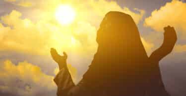 Imagem de uma santa orando com as mãos para cima.