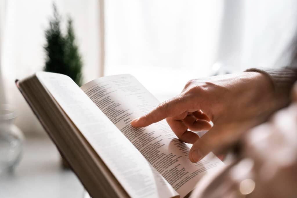 Pessoa acompanhando a leitura da Bíblia com os dedos.