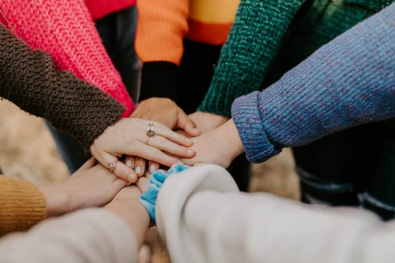 Mãos de várias mulheres sobrepostas uma à outra, em sinal de união.