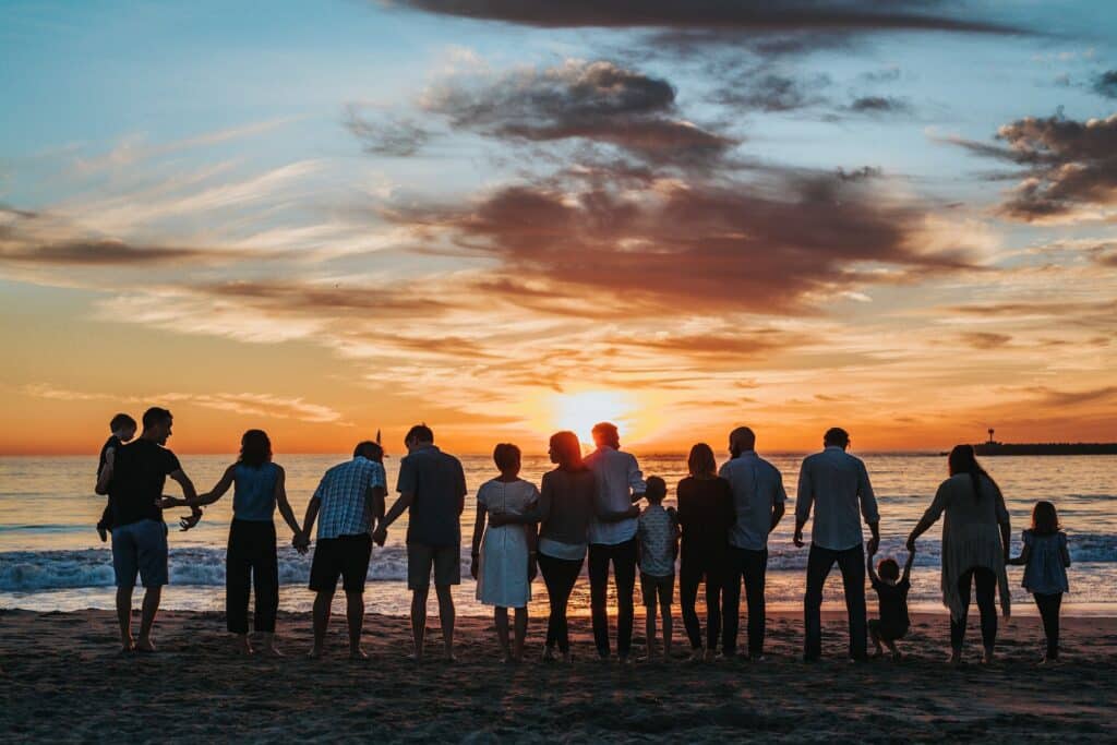 Foto de família em frente ao mar. Ao fundo está um por do sol.