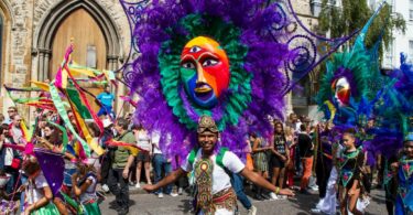 Homem dançando com uma fantasia no Notting Hill Carnival