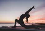 silhueta de mulher praticando yoga na praia, ao pôr do Sol.