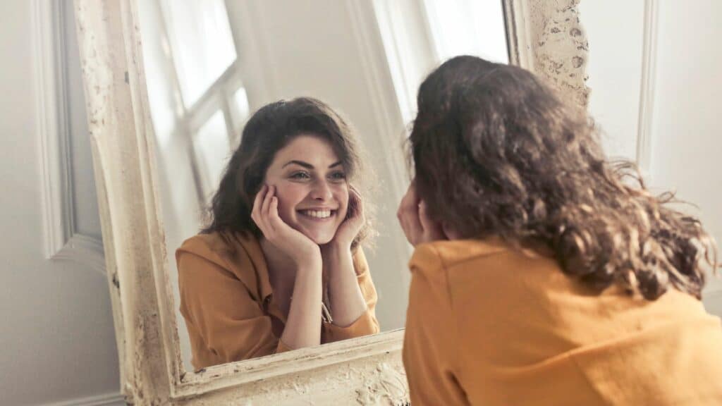 Imagem de uma mulher sorrindo enquanto olha para o espelho