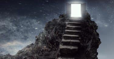 Imagem de uma porta aberta e saindo uma luz dela acima de uma rocha, e uma escada que leva até ela. Ao seu redor o céu a noite, estrelado.