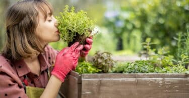 Imagem de uma mulher cheirando as plantas de olhos fechados