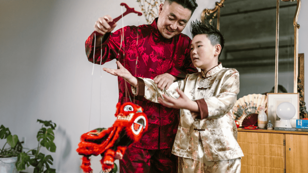 Homem e criança brincando com um brinquedo típico do ano novo chinês, usando roupas tradicionais.