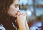 Garota com os olhos fechados rezando