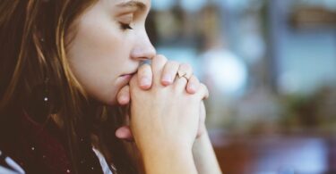 Garota com os olhos fechados rezando
