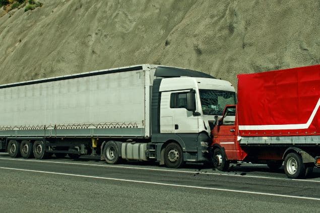 Dois caminhões se colidindo no acostamento de uma estrada