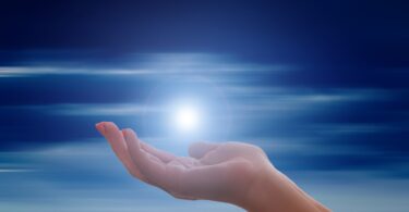 Imagem de uma mão estendida com uma luz em cima e o céu ilustrados.