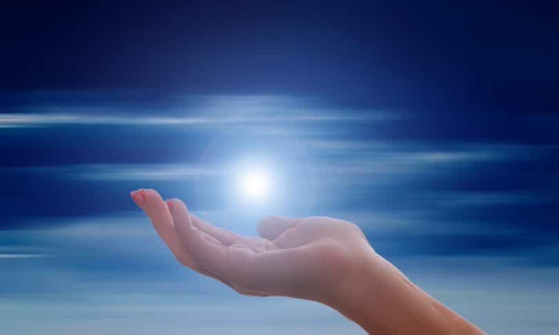 Imagem de uma mão estendida com uma luz em cima e o céu ilustrados.