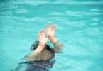 Criança embaixo d'água com os braços esticados