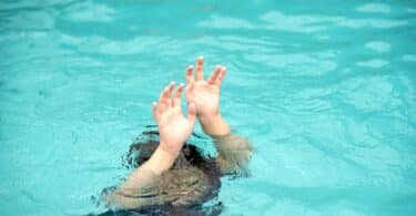 Criança embaixo d'água com os braços esticados