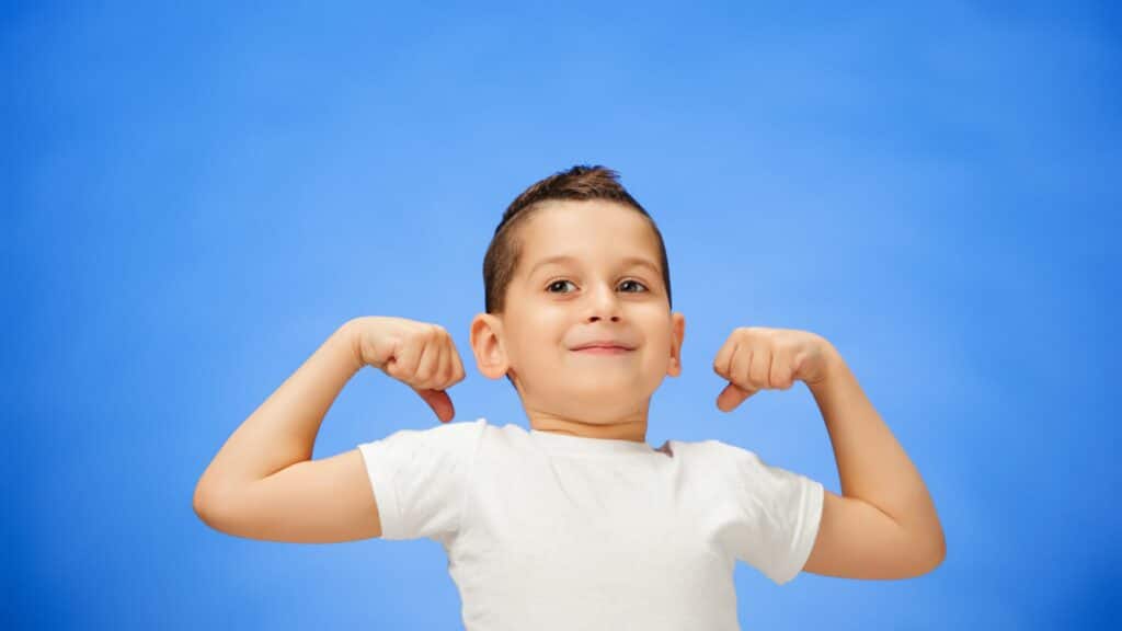Imagem de um garoto com os braços levantados em sinal de força em um fundo azul