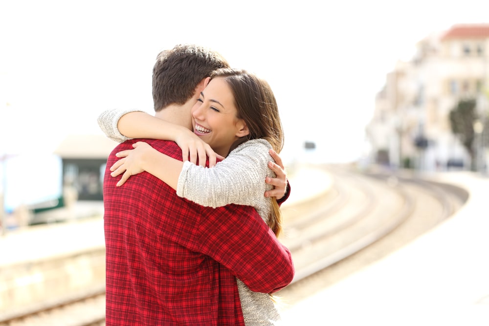 Casal feliz se abraçando em uma estação de trem.