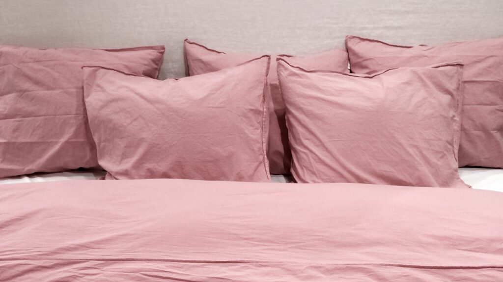 Imagem de travesseiros e uma cama com lençóis e fronhas cor de rosa