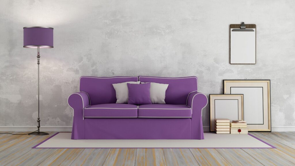 Imagem de uma sala clara com o sofá, o abajur e as bordas do tapete na cor roxa.