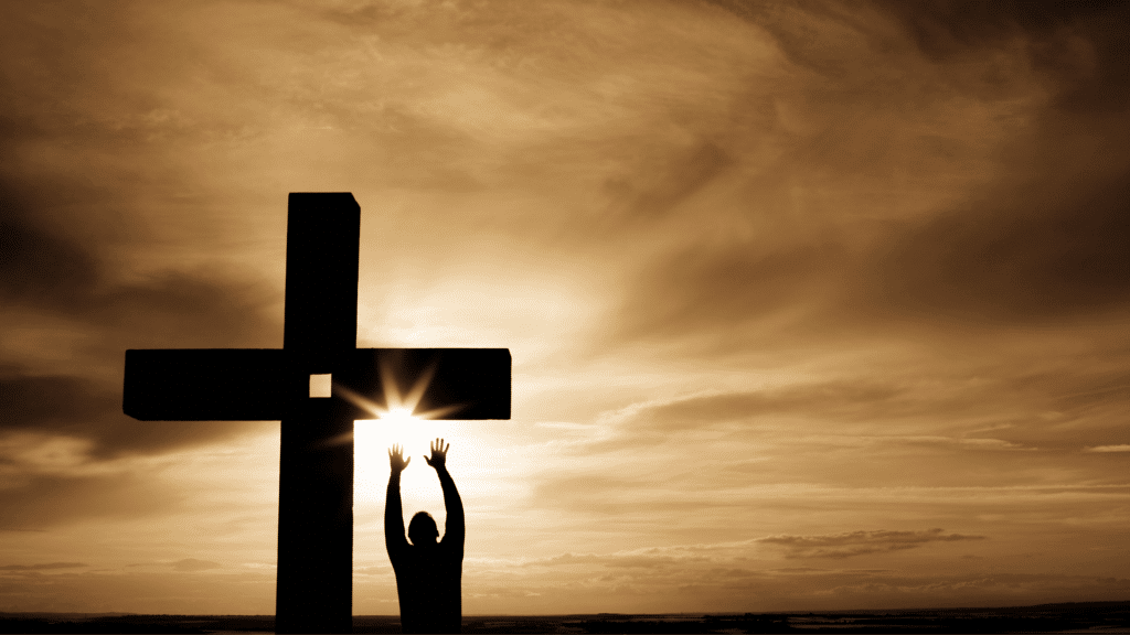 Silhueta de uma pessoa e uma cruz e ao fundo o céu