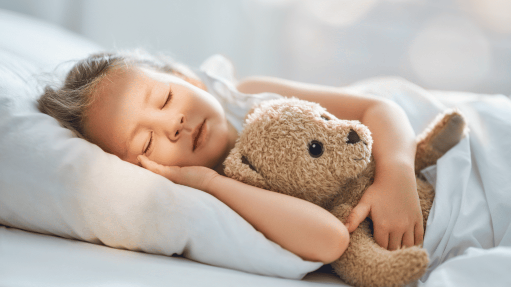 Criança branca deitada segurando um urso de pelúcia