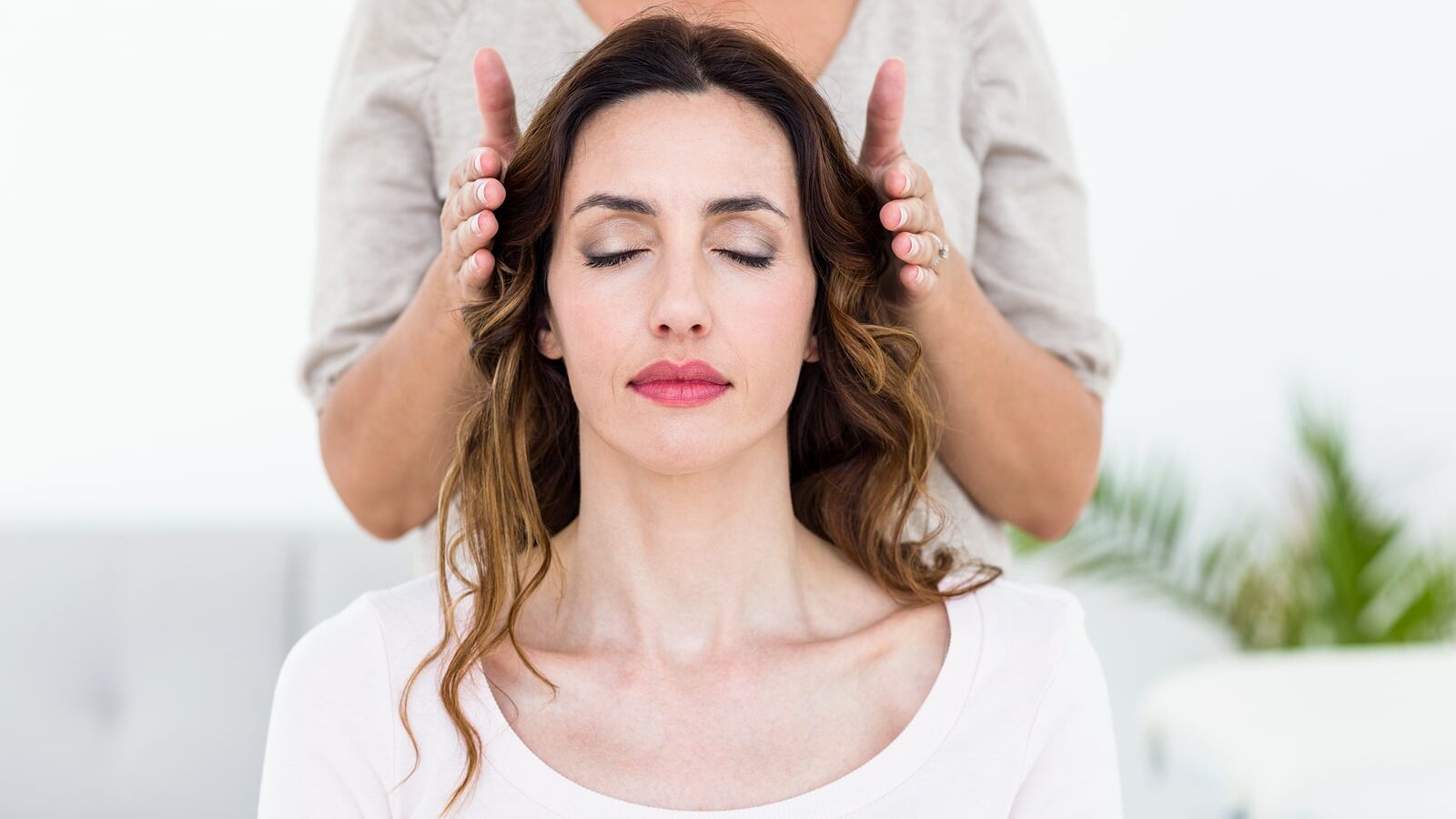 Calm woman receiving reiki treatment on white background