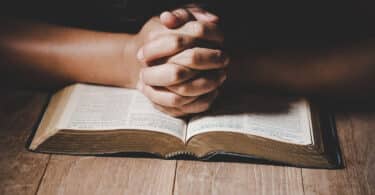 Pessoa com mãos apoiadas em bíblia