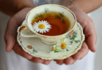 Xícara de chá com várias flores pequenas distribuídas pelo líquido e pelo píres