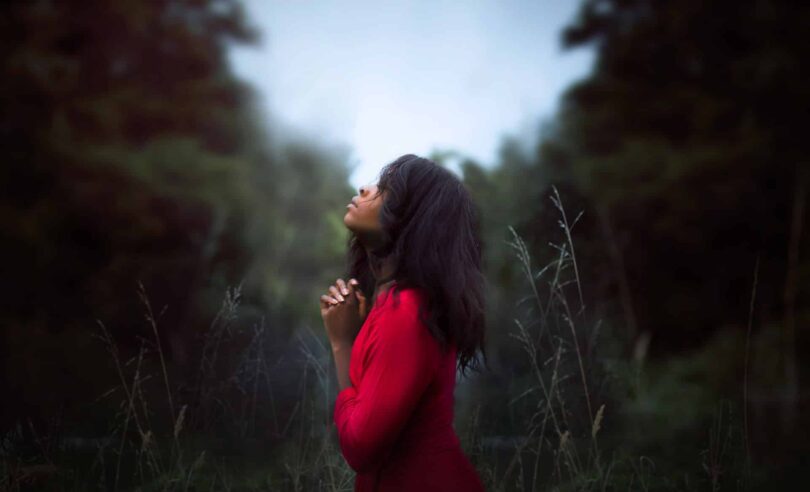 Mulher de vermelho orando aos céus.