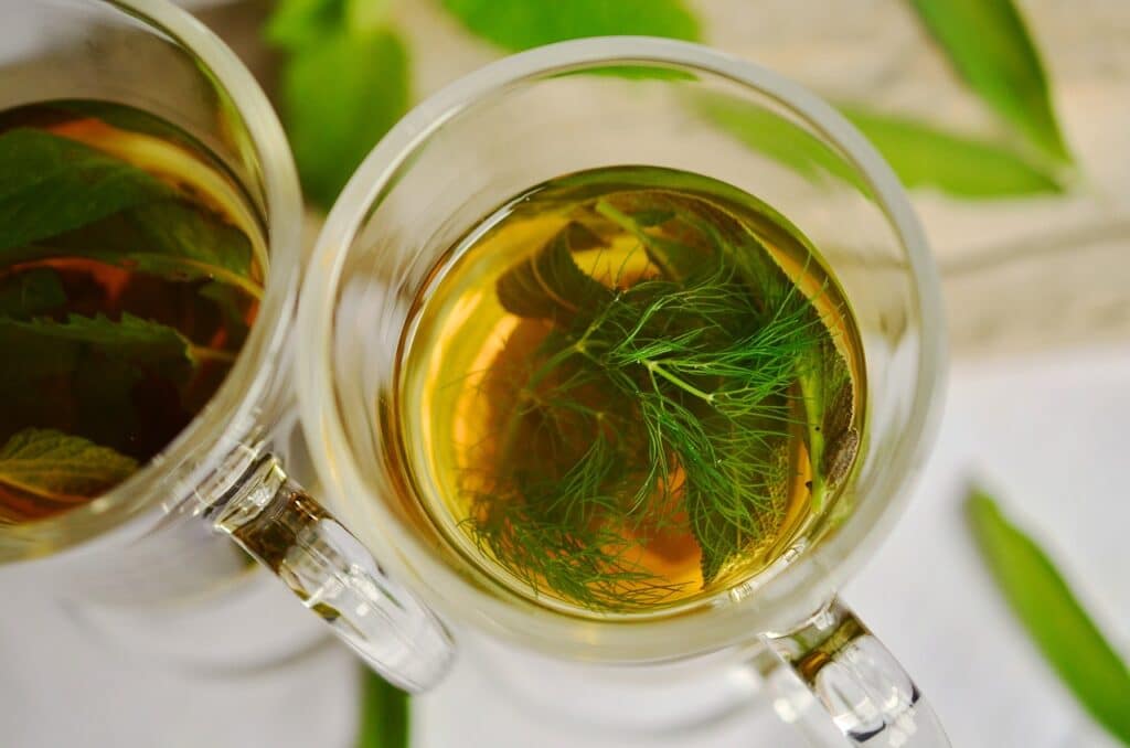 Caneca de vidro transparente com chá de erva-doce