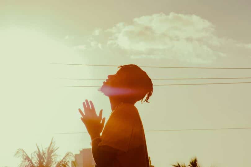 Homem orando ao ar livre, direcionado ao céu.