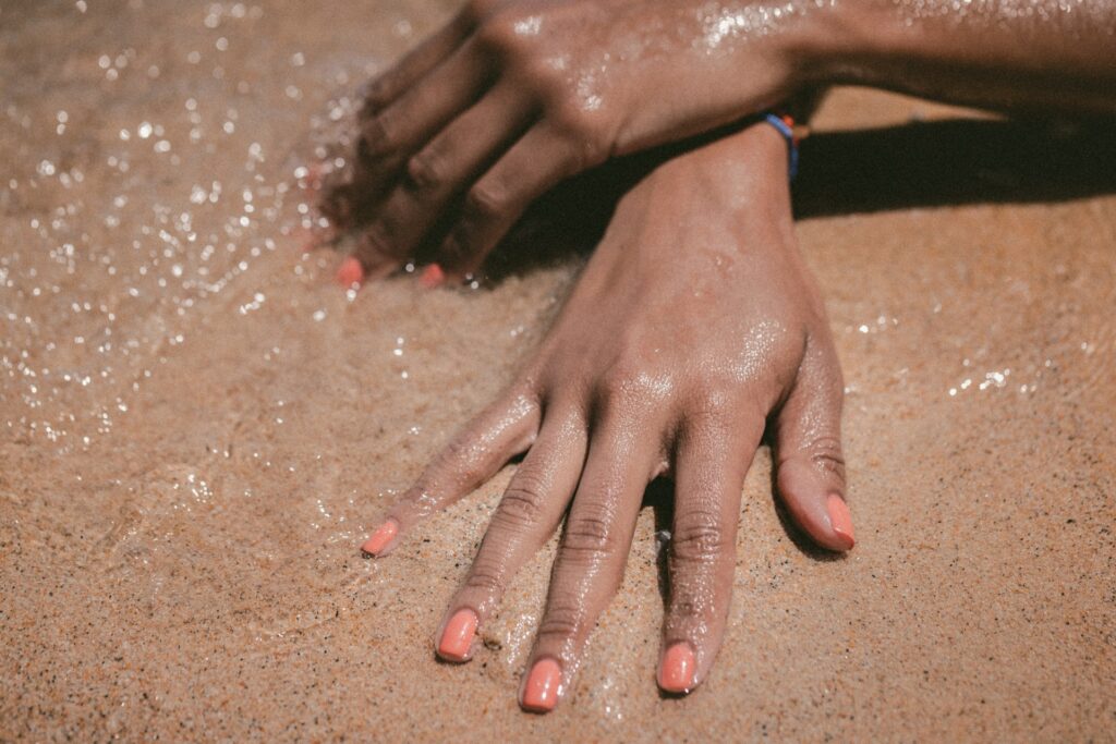 Mãos femininas na areia da praia.