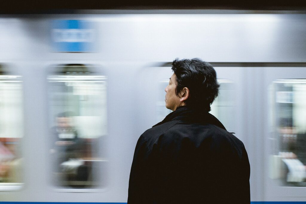 Homem de costas, na frente de um trem em movimento.