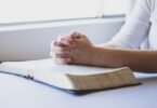 Mãos sobre uma Bíblia, em posição de oração
