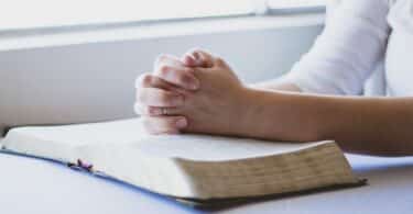 Mãos sobre uma Bíblia, em posição de oração