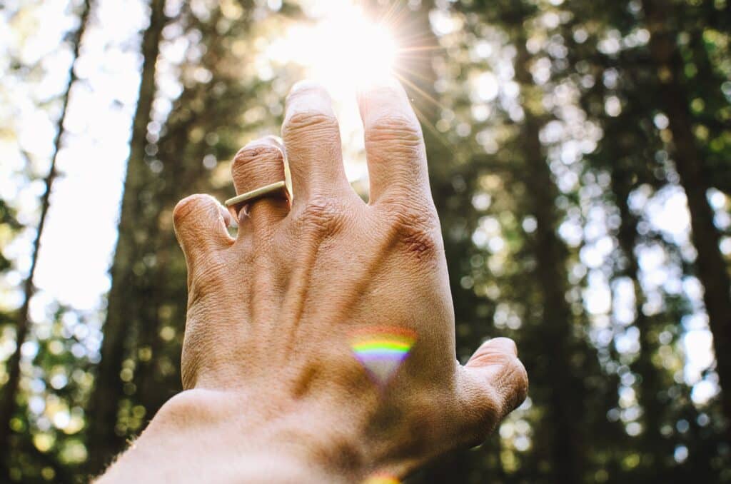 Mão masculina estendida em direção ao Sol.