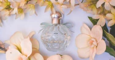 Frasco de perfume rodeado por flores.