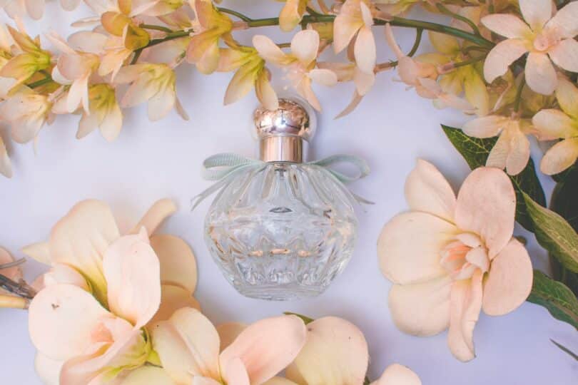 Frasco de perfume rodeado por flores.