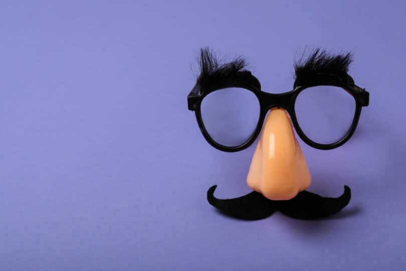 Óculos de disfarce, com bigode e nariz falso, sobre um plano roxo.