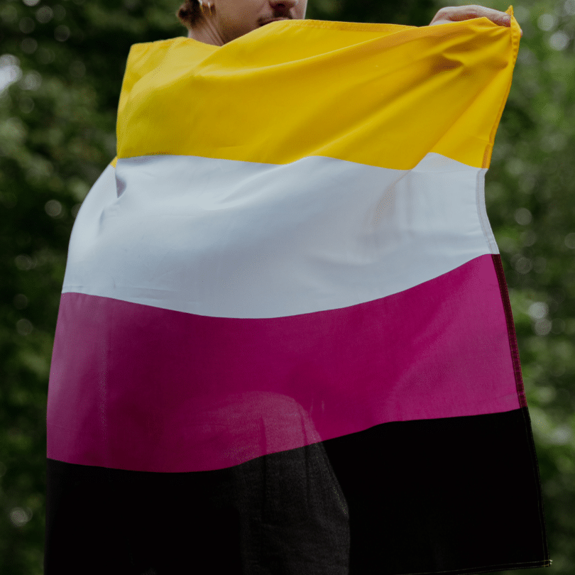 Homem segurando a bandeira do movimento não binário