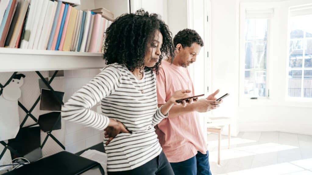 Imagem de um casal, cada um segurando seu celular sem conversar entre si