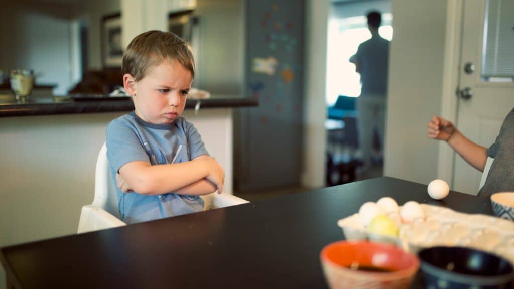 Imagem de um menino pequeno com os braços cuzados e com semblante de insatisfação