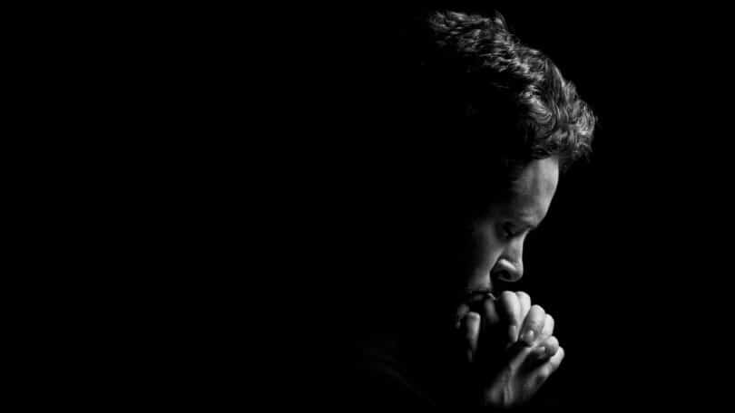 Imagem de um homem fazendo oração em um fundo preto