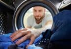 Imagem de um homeme colocando roupas para lavar dentro da máquina
