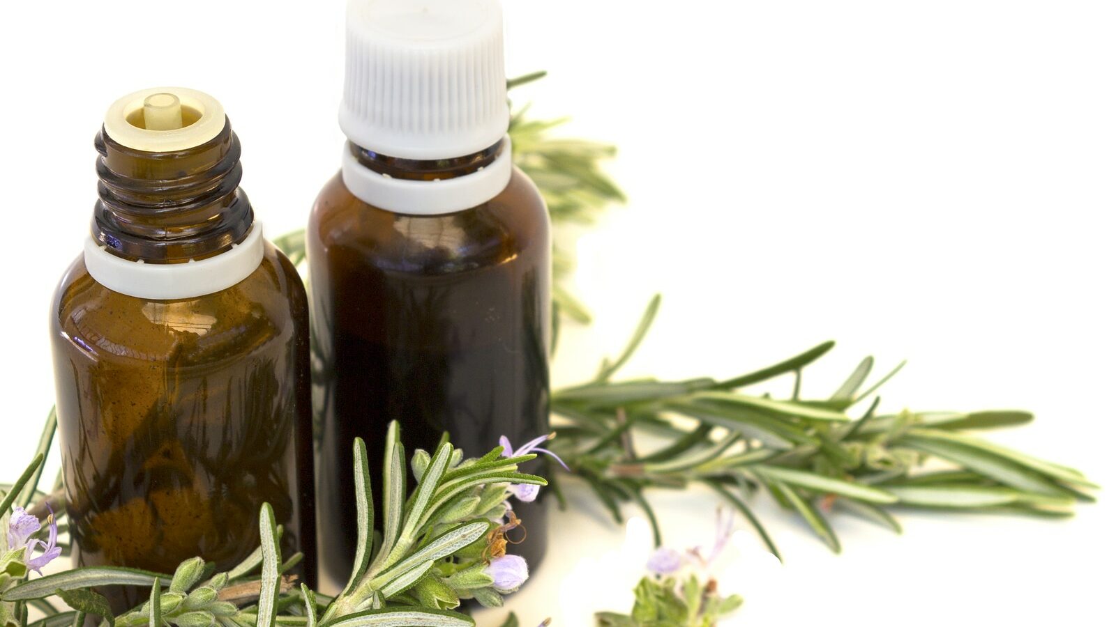 Essential aroma oil with rosemary on white background. Selective focus.