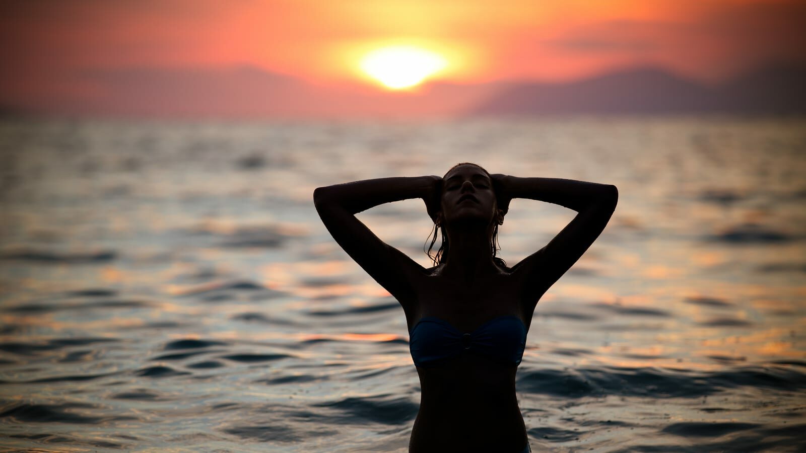 Gorgeous sexy fit woman silhouette swimming in sunset.Free happy woman enjoying sunset. Beautiful woman in water embracing the golden sunshine glow of sunset, enjoying peace, serenity in nature.